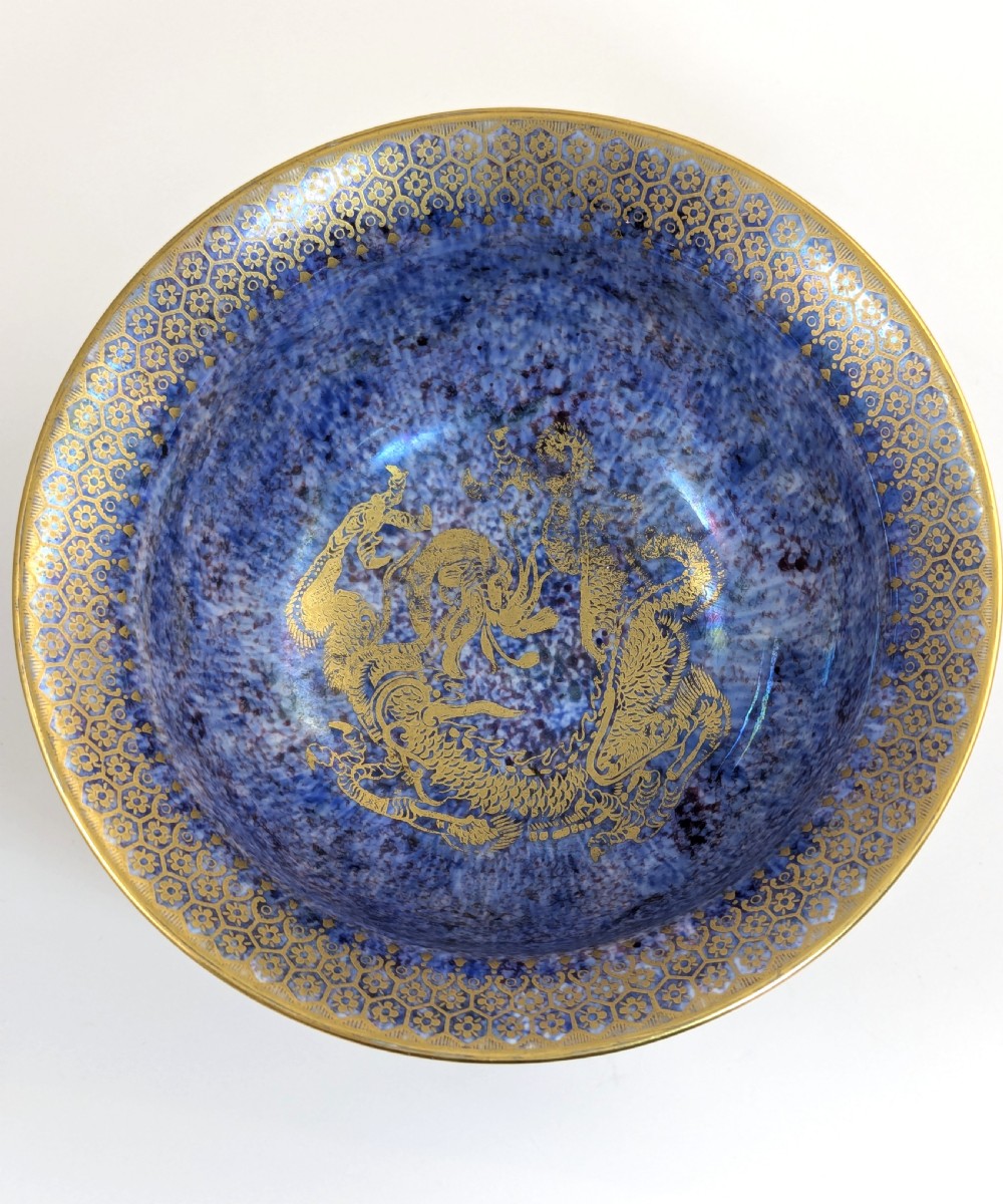 A circular ceramic bowl displaying a mottled orange and gold exterior with a deep speckled blue interior bordered by detailed gilt geometric patterns. View VI