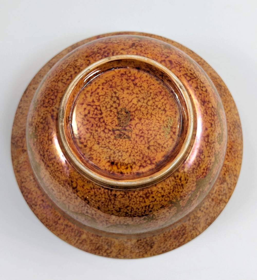 A circular ceramic bowl displaying a mottled orange and gold exterior with a deep speckled blue interior bordered by detailed gilt geometric patterns. View VII