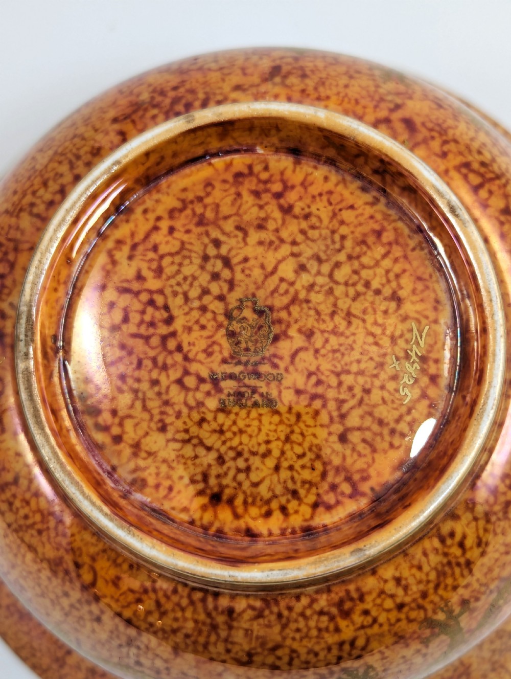 A circular ceramic bowl displaying a mottled orange and gold exterior with a deep speckled blue interior bordered by detailed gilt geometric patterns. View VIII
