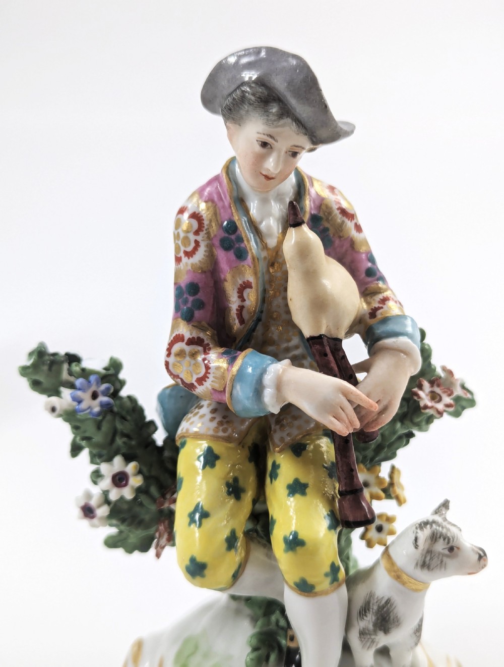 Pair of nineteenth-century Dresden porcelain figurines depicting a male bagpipe player with a dog and a female lute player with a lamb, both styled in Rococo attire on ornate bases. View X