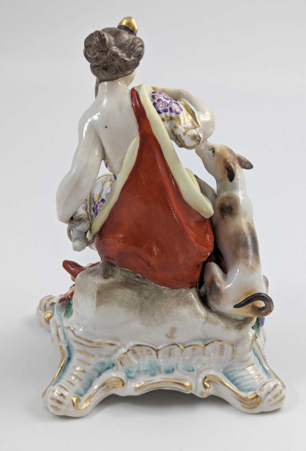 An 18th-century Chelsea soft-paste porcelain figurine depicting Diana the Huntress seated on a Rococo scroll base with a hound and quiver. View IV