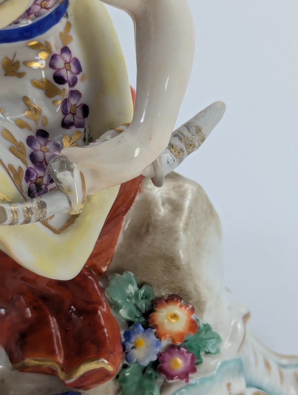 An 18th-century Chelsea soft-paste porcelain figurine depicting Diana the Huntress seated on a Rococo scroll base with a hound and quiver. View XIII
