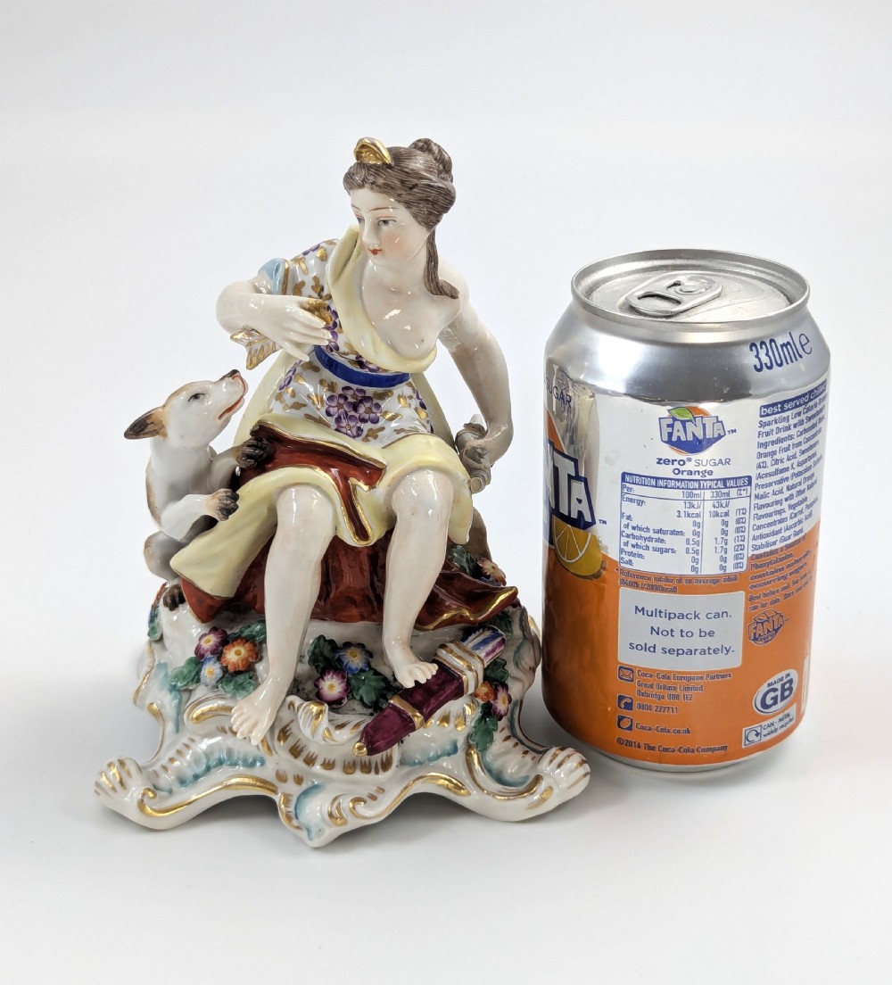 An 18th-century Chelsea soft-paste porcelain figurine depicting Diana the Huntress seated on a Rococo scroll base with a hound and quiver. View XIV