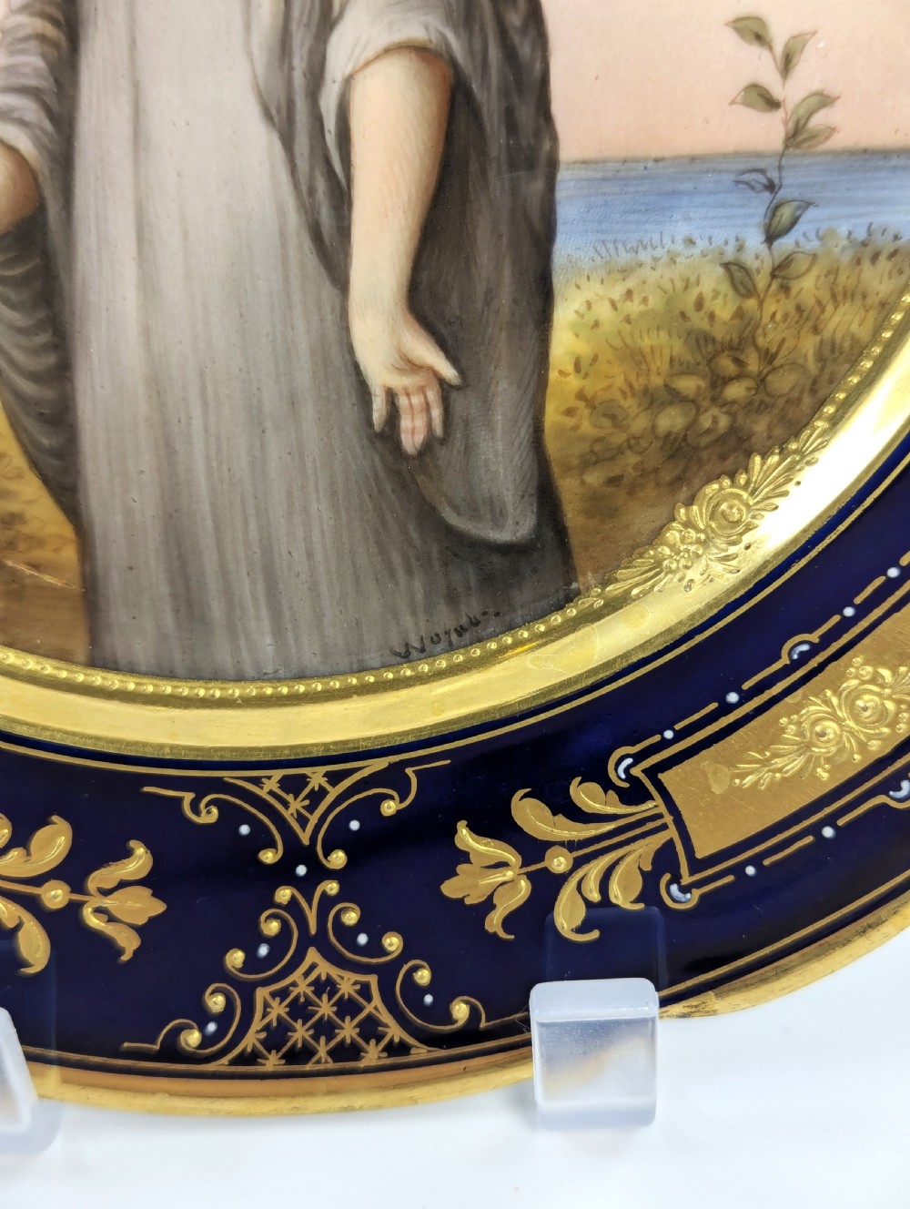 A circular porcelain cabinet plate with a central hand-painted portrait of a woman in draped attire set within a cobalt blue rim embellished with gold gilding. View III
