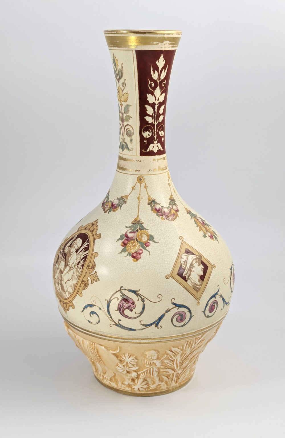 A late 19th-century Wedgwood ceramic vase featuring a slender neck, bulbous body decorated with classical cartouches and gilt details, resting on a carved relief base. View II