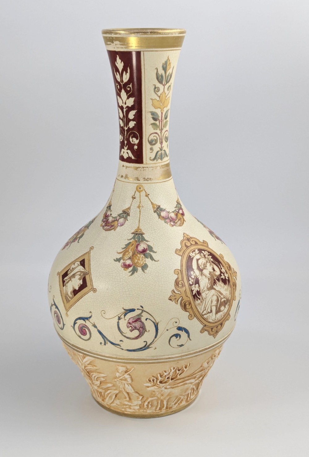 A late 19th-century Wedgwood ceramic vase featuring a slender neck, bulbous body decorated with classical cartouches and gilt details, resting on a carved relief base. View IV
