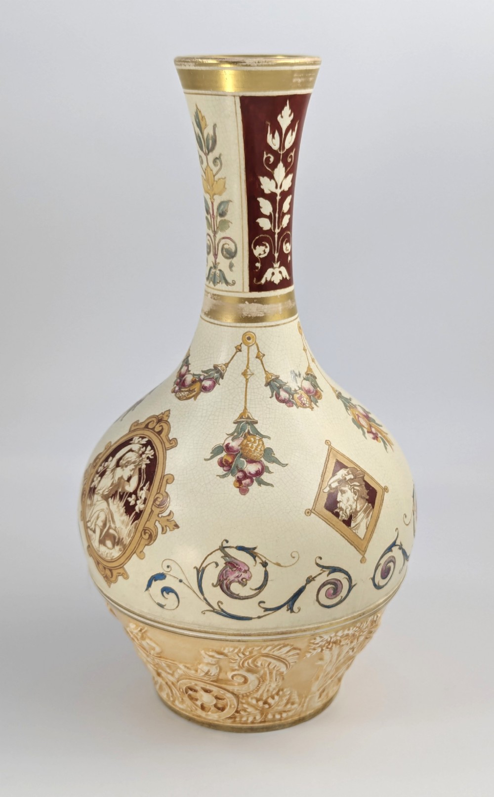A late 19th-century Wedgwood ceramic vase featuring a slender neck, bulbous body decorated with classical cartouches and gilt details, resting on a carved relief base. View VI