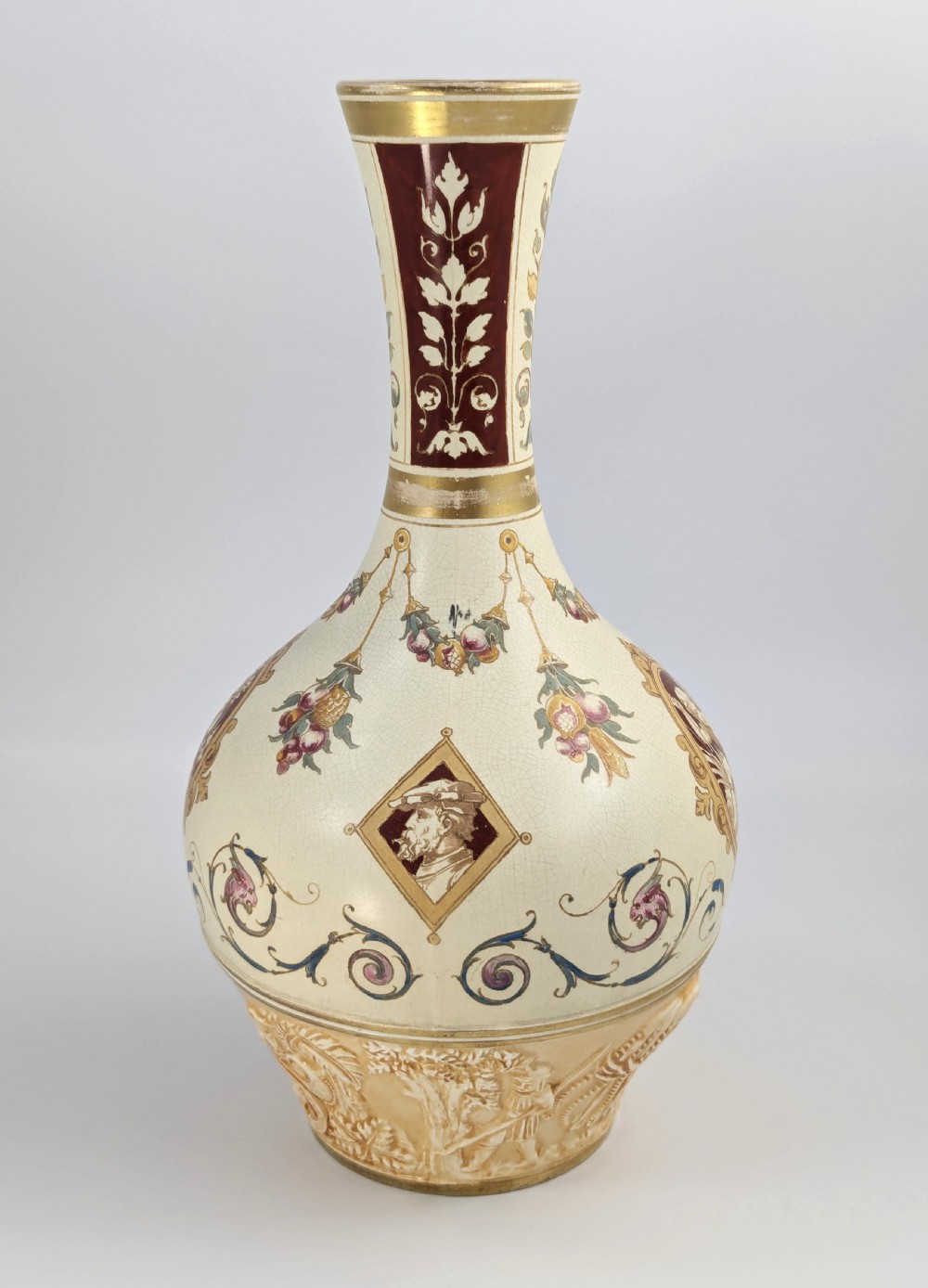 A late 19th-century Wedgwood ceramic vase featuring a slender neck, bulbous body decorated with classical cartouches and gilt details, resting on a carved relief base. View VII