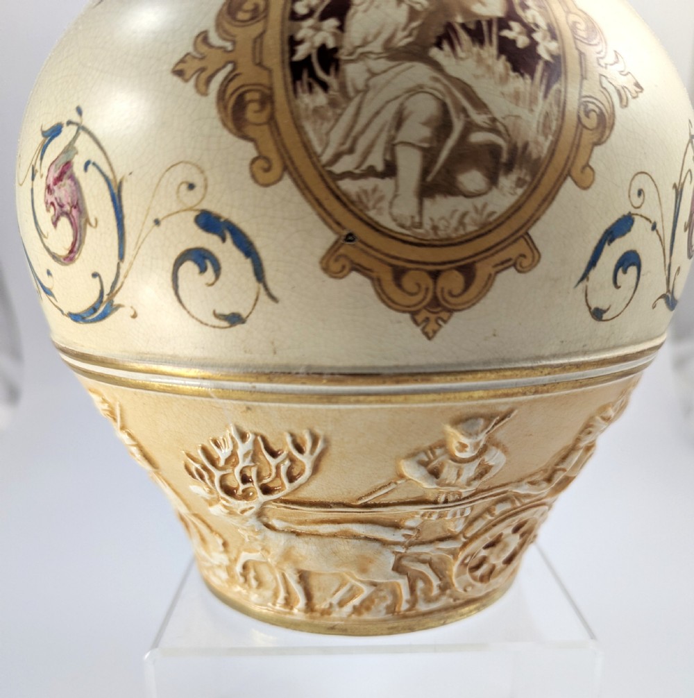 A late 19th-century Wedgwood ceramic vase featuring a slender neck, bulbous body decorated with classical cartouches and gilt details, resting on a carved relief base. View XI