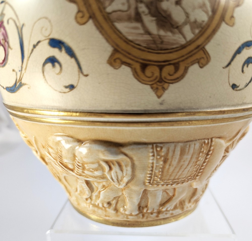 A late 19th-century Wedgwood ceramic vase featuring a slender neck, bulbous body decorated with classical cartouches and gilt details, resting on a carved relief base. View XIII