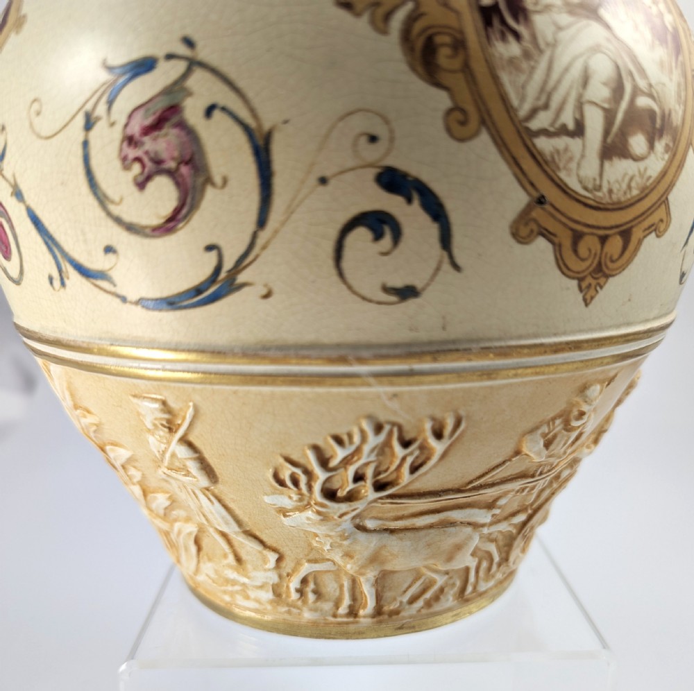 A late 19th-century Wedgwood ceramic vase featuring a slender neck, bulbous body decorated with classical cartouches and gilt details, resting on a carved relief base. View XV