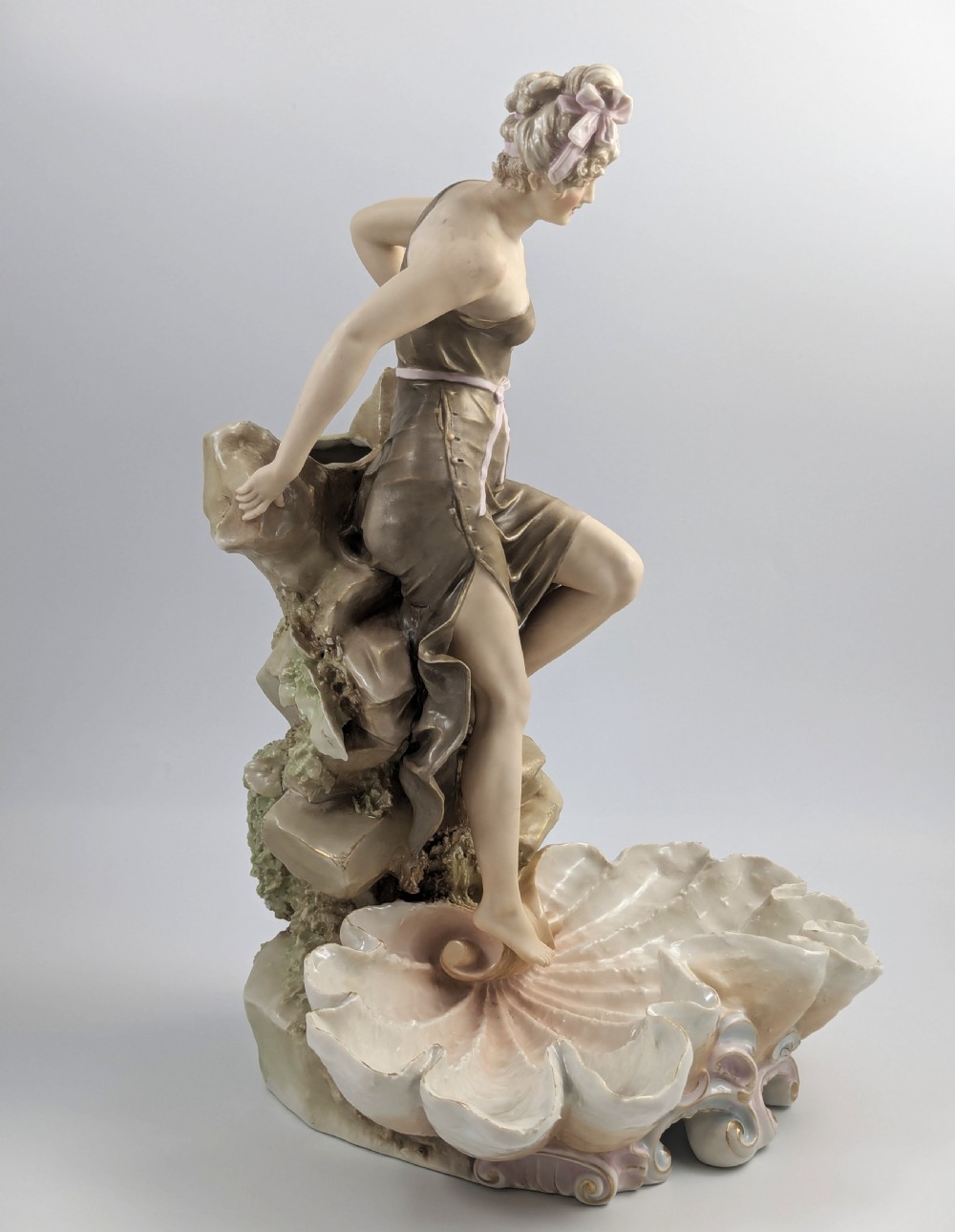 An Art Nouveau Royal Dux porcelain centrepiece depicting a draped female bather standing atop rockwork above a large shell-shaped basin. View VI