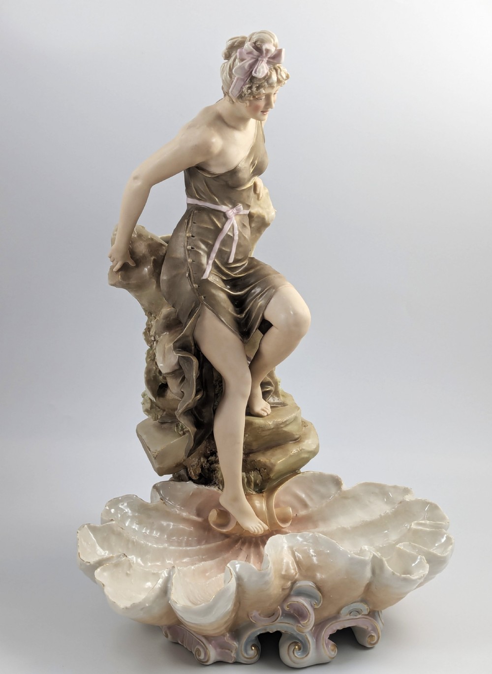 An Art Nouveau Royal Dux porcelain centrepiece depicting a draped female bather standing atop rockwork above a large shell-shaped basin. View VII