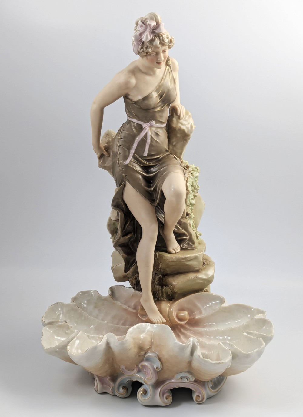 An Art Nouveau Royal Dux porcelain centrepiece depicting a draped female bather standing atop rockwork above a large shell-shaped basin. View VIII