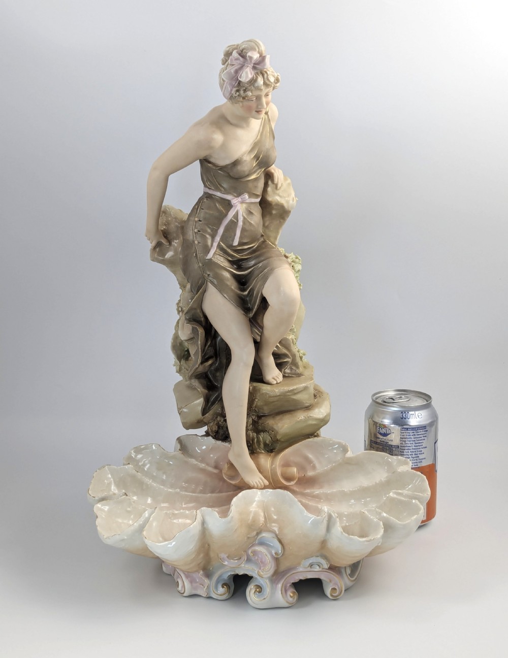 An Art Nouveau Royal Dux porcelain centrepiece depicting a draped female bather standing atop rockwork above a large shell-shaped basin. View XIV