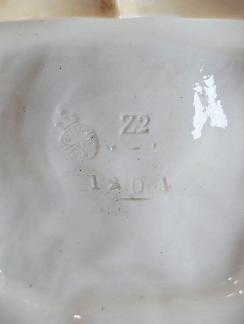 A late nineteenth-century Royal Worcester blush ivory porcelain figurine depicting a seated Indian craftsman working on an ornate pedestal base. View X