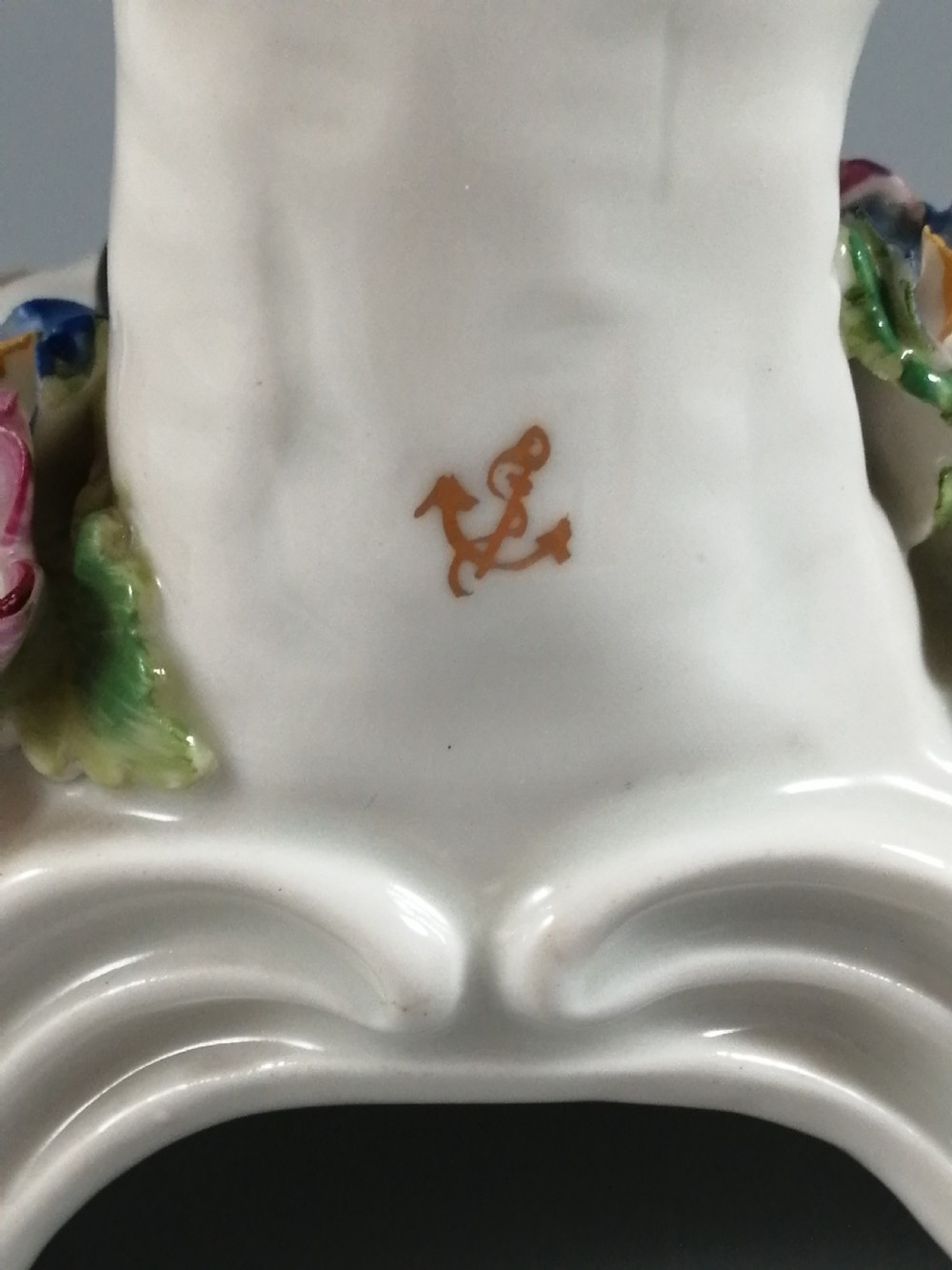 An 18th-century Bow porcelain figurine depicting a boy drummer wearing a pink coat, blue waistcoat, and tricorn hat on a Rococo scroll base with floral encrustations. View VI