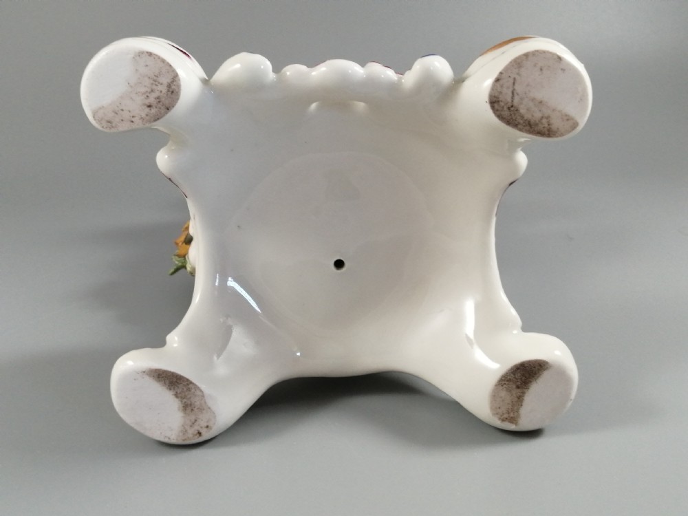 An 18th-century Bow porcelain figurine depicting a boy drummer wearing a pink coat, blue waistcoat, and tricorn hat on a Rococo scroll base with floral encrustations. View XI