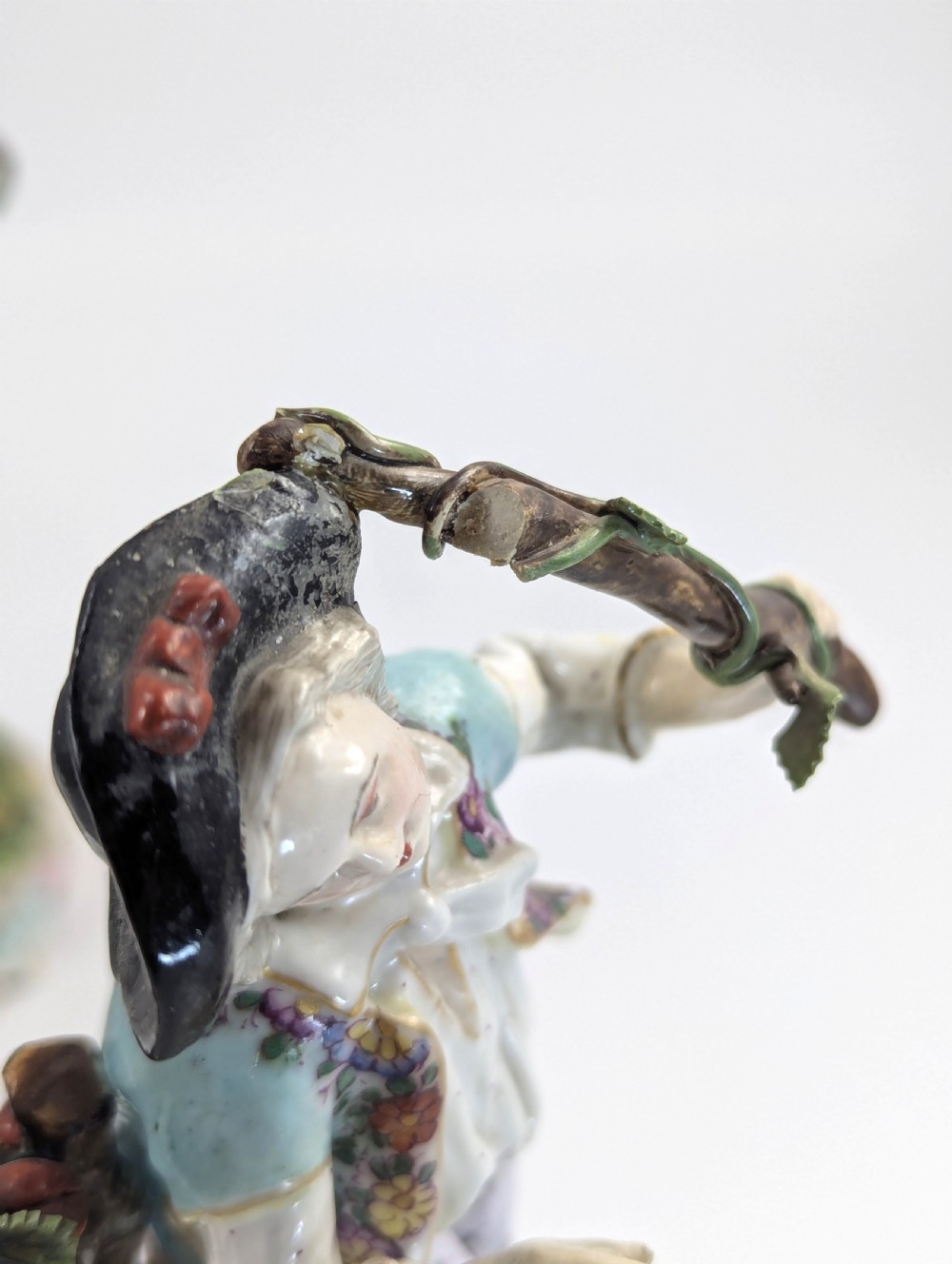 A pair of 18th-century German porcelain figurines depicting a male and female gardener standing beside fruiting trees on Rococo scrollwork bases. View X