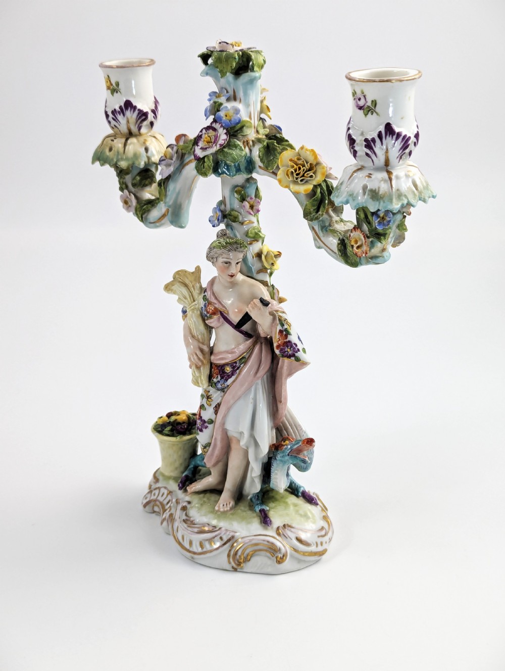 A nineteenth-century Dresden porcelain three-light candelabra featuring a central allegorical figure draped in floral fabric standing on a gilded Rococo base surrounded by encrusted porcelain flowers. View II