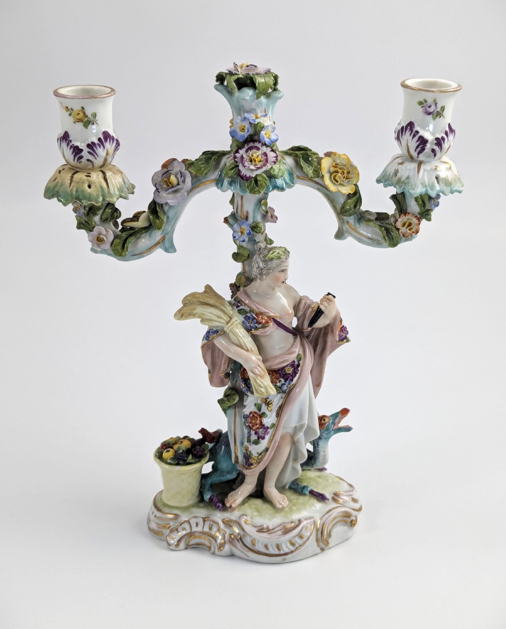 A nineteenth-century Dresden porcelain three-light candelabra featuring a central allegorical figure draped in floral fabric standing on a gilded Rococo base surrounded by encrusted porcelain flowers. View VII