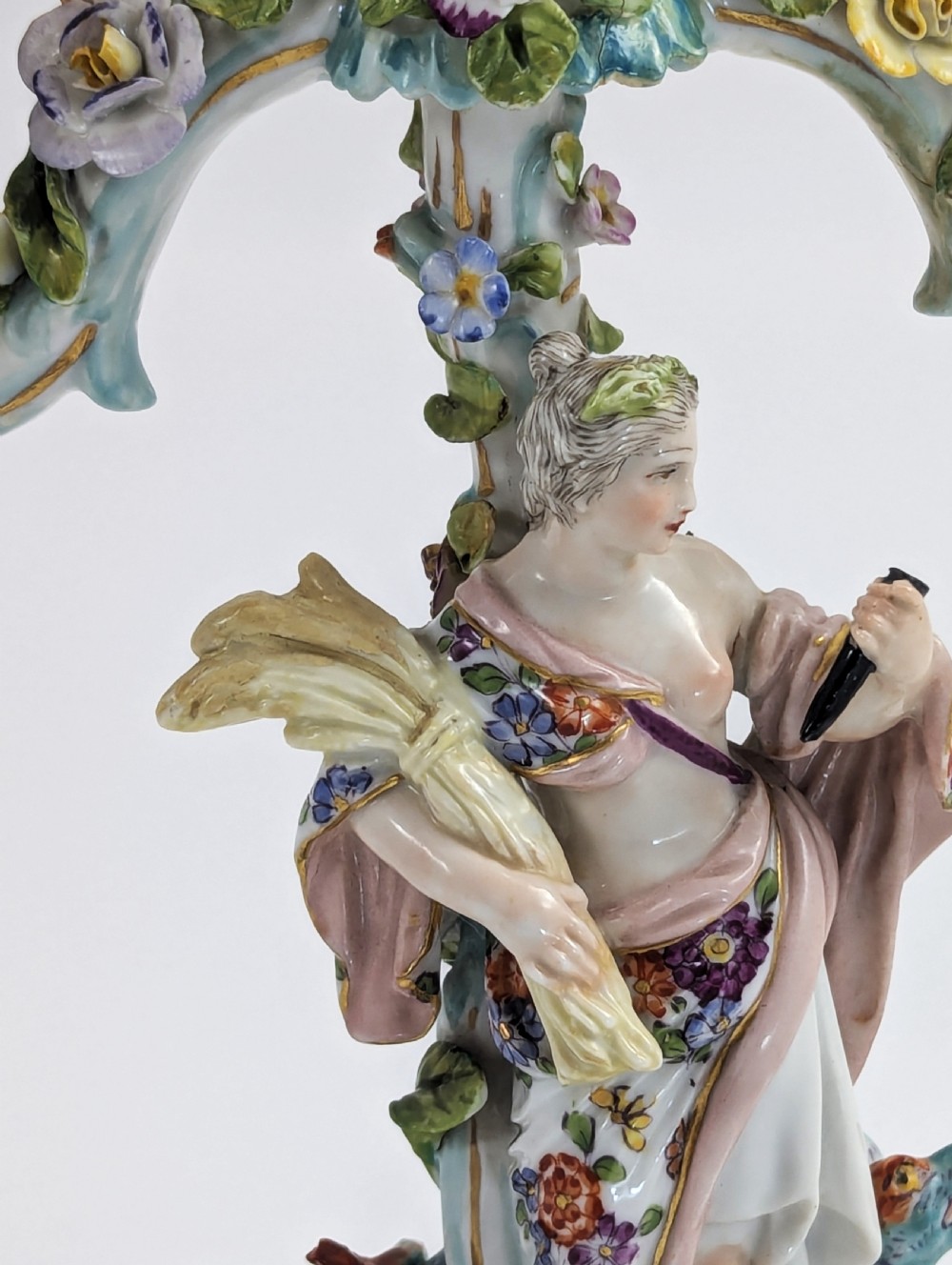 A nineteenth-century Dresden porcelain three-light candelabra featuring a central allegorical figure draped in floral fabric standing on a gilded Rococo base surrounded by encrusted porcelain flowers. View VIII