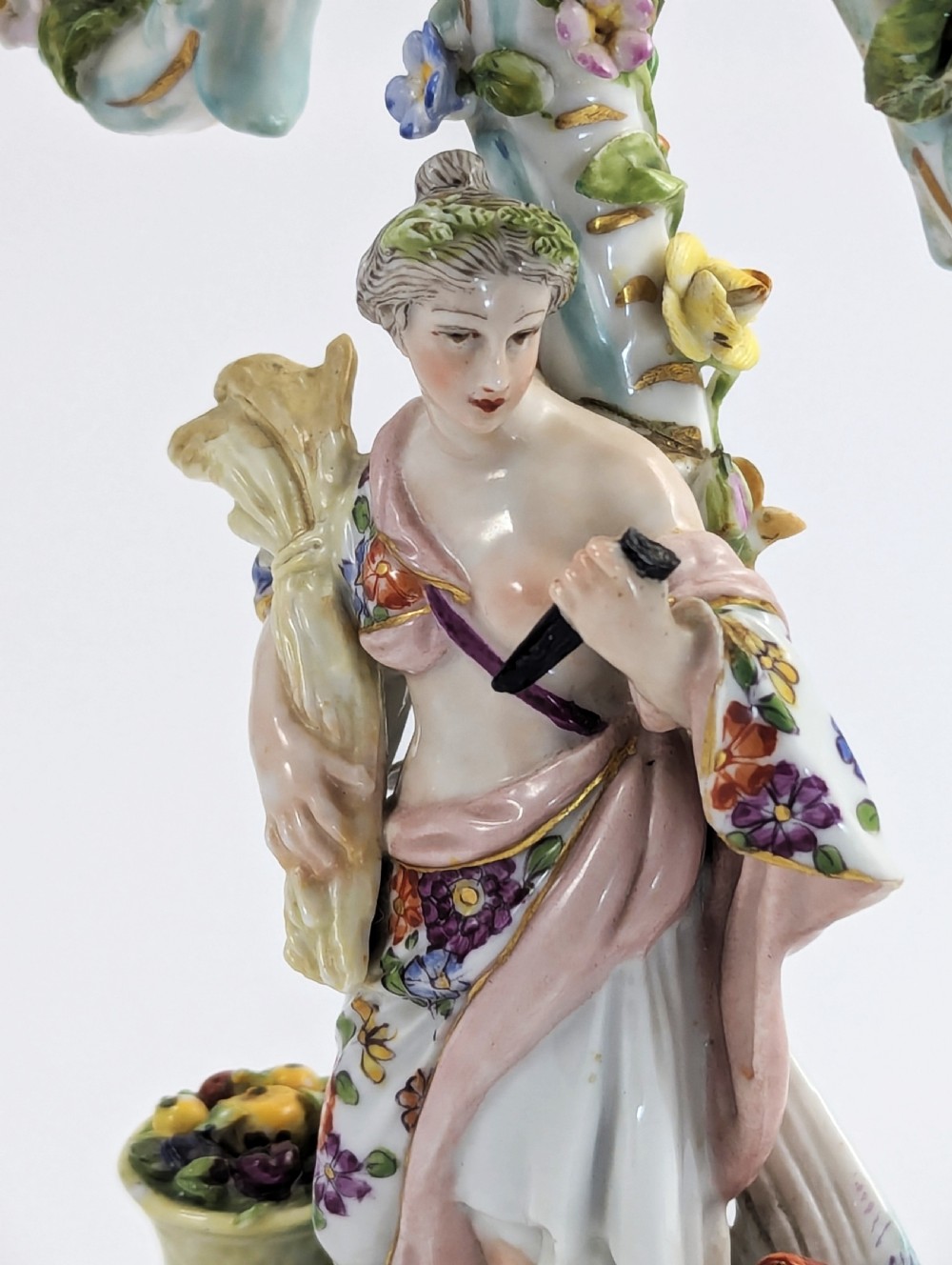 A nineteenth-century Dresden porcelain three-light candelabra featuring a central allegorical figure draped in floral fabric standing on a gilded Rococo base surrounded by encrusted porcelain flowers. View IX