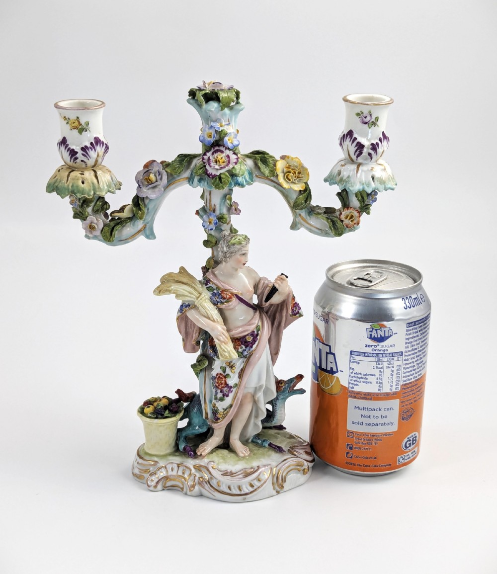 A nineteenth-century Dresden porcelain three-light candelabra featuring a central allegorical figure draped in floral fabric standing on a gilded Rococo base surrounded by encrusted porcelain flowers. View XII