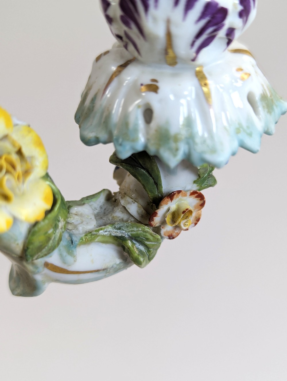 A nineteenth-century Dresden porcelain three-light candelabra featuring a central allegorical figure draped in floral fabric standing on a gilded Rococo base surrounded by encrusted porcelain flowers. View XIV