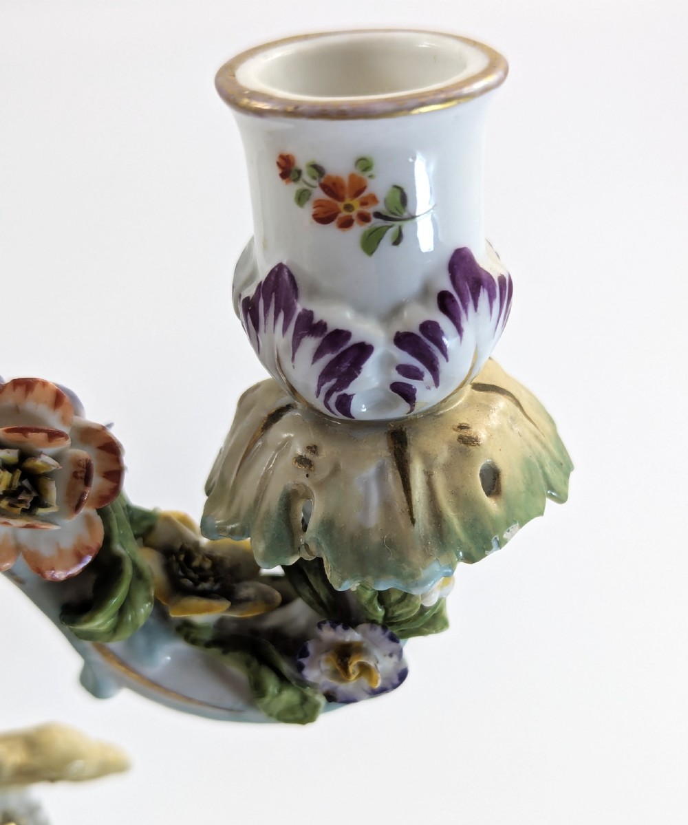 A nineteenth-century Dresden porcelain three-light candelabra featuring a central allegorical figure draped in floral fabric standing on a gilded Rococo base surrounded by encrusted porcelain flowers. View XV
