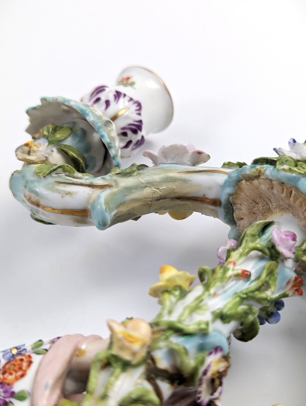 A nineteenth-century Dresden porcelain three-light candelabra featuring a central allegorical figure draped in floral fabric standing on a gilded Rococo base surrounded by encrusted porcelain flowers. View XVI