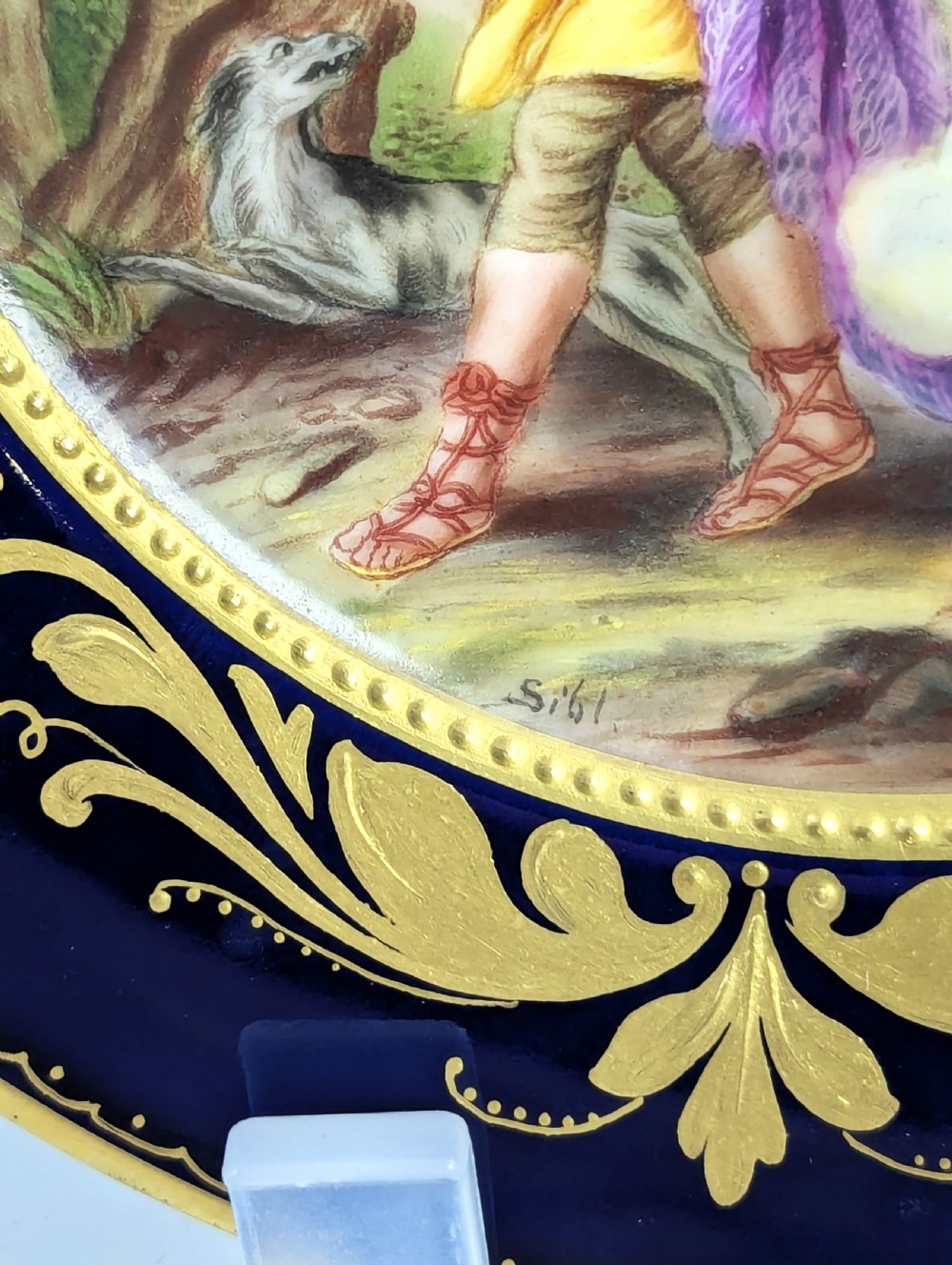 A circular porcelain cabinet plate featuring a central hand-painted scene of Aurora and Cephalus framed by a wide cobalt blue border with intricate gold scrollwork gilding. View III