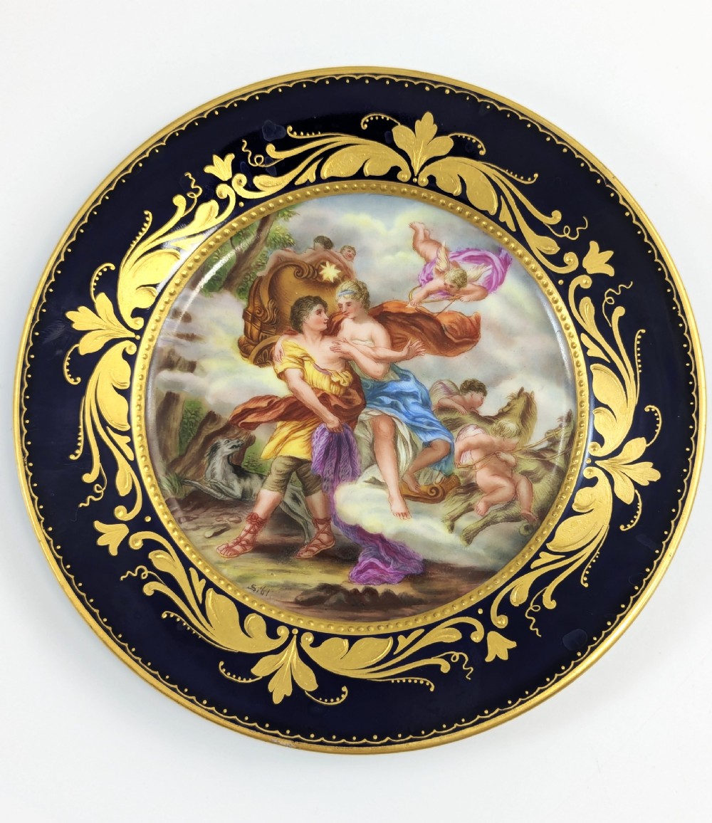 A circular porcelain cabinet plate featuring a central hand-painted scene of Aurora and Cephalus framed by a wide cobalt blue border with intricate gold scrollwork gilding. View VI