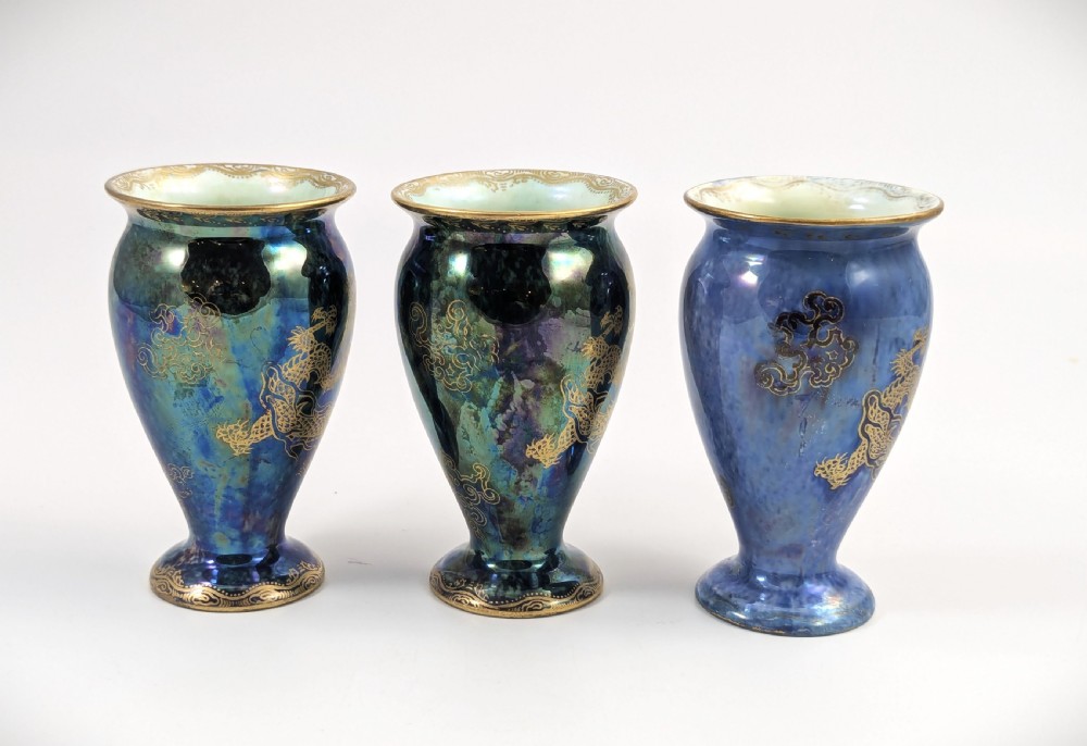 A trio of small blue iridescent ceramic bud vases featuring gilded dragon motifs and flared upper rims. View V