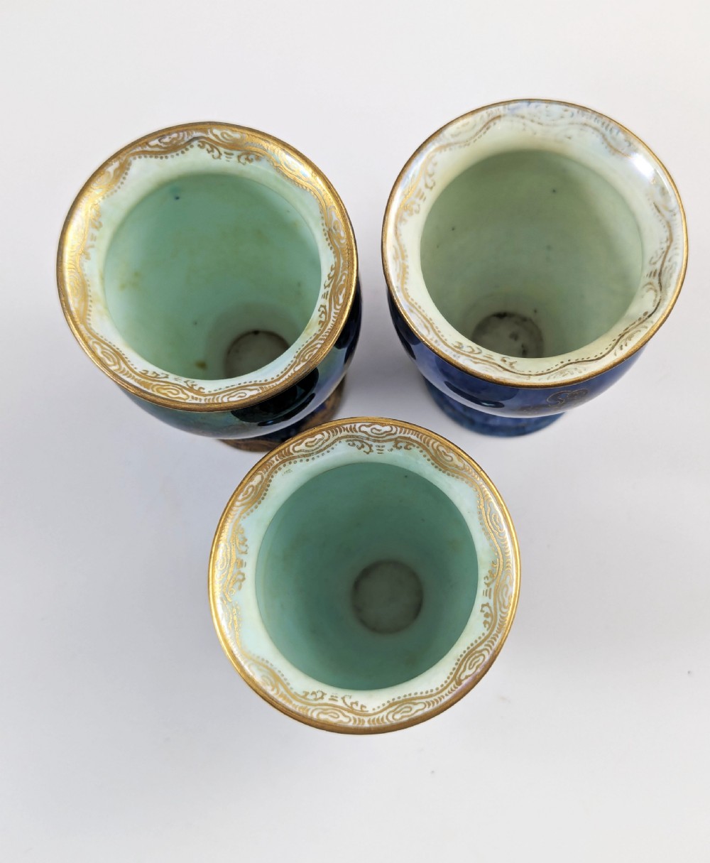 A trio of small blue iridescent ceramic bud vases featuring gilded dragon motifs and flared upper rims. View VI