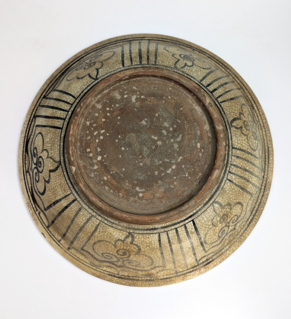 A circular antique ceramic dish featuring a central underglaze grey fish design on a crazed cream ground. View IV