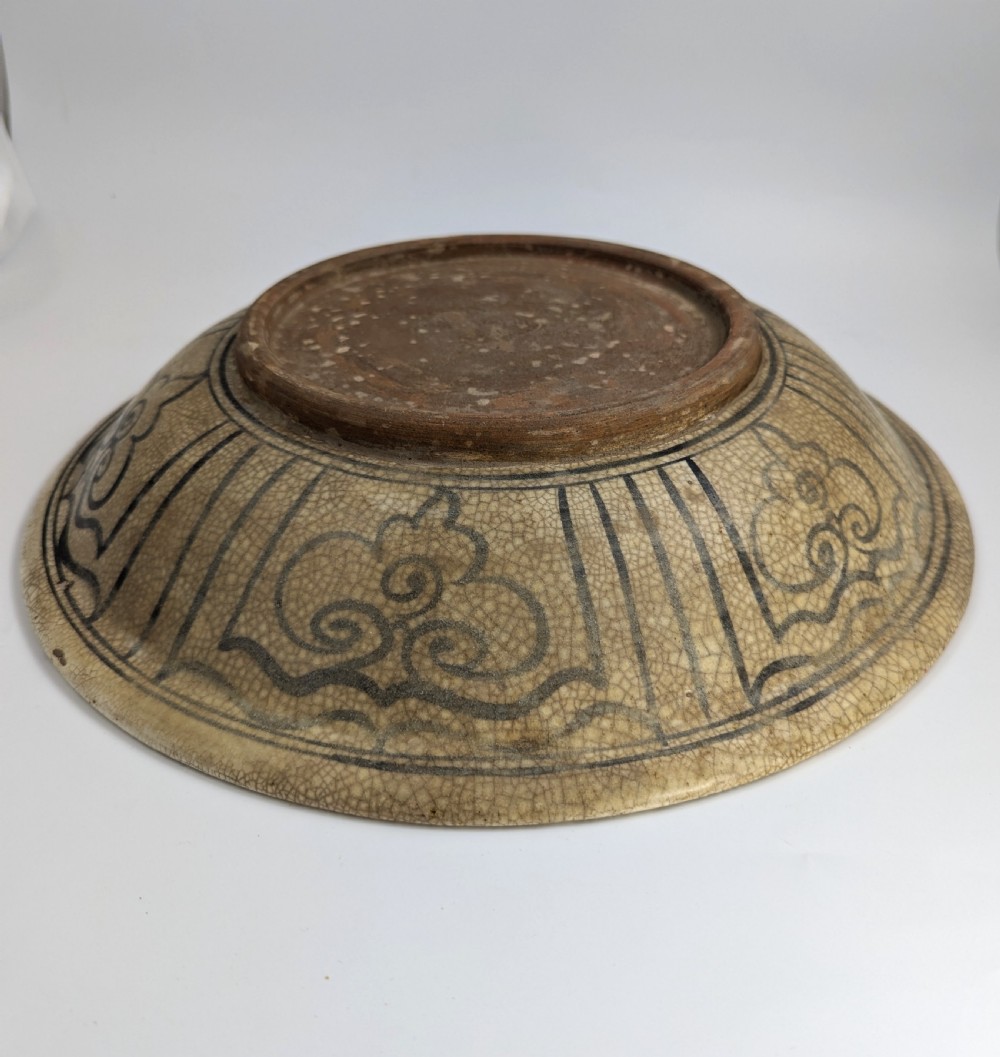 A circular antique ceramic dish featuring a central underglaze grey fish design on a crazed cream ground. View V