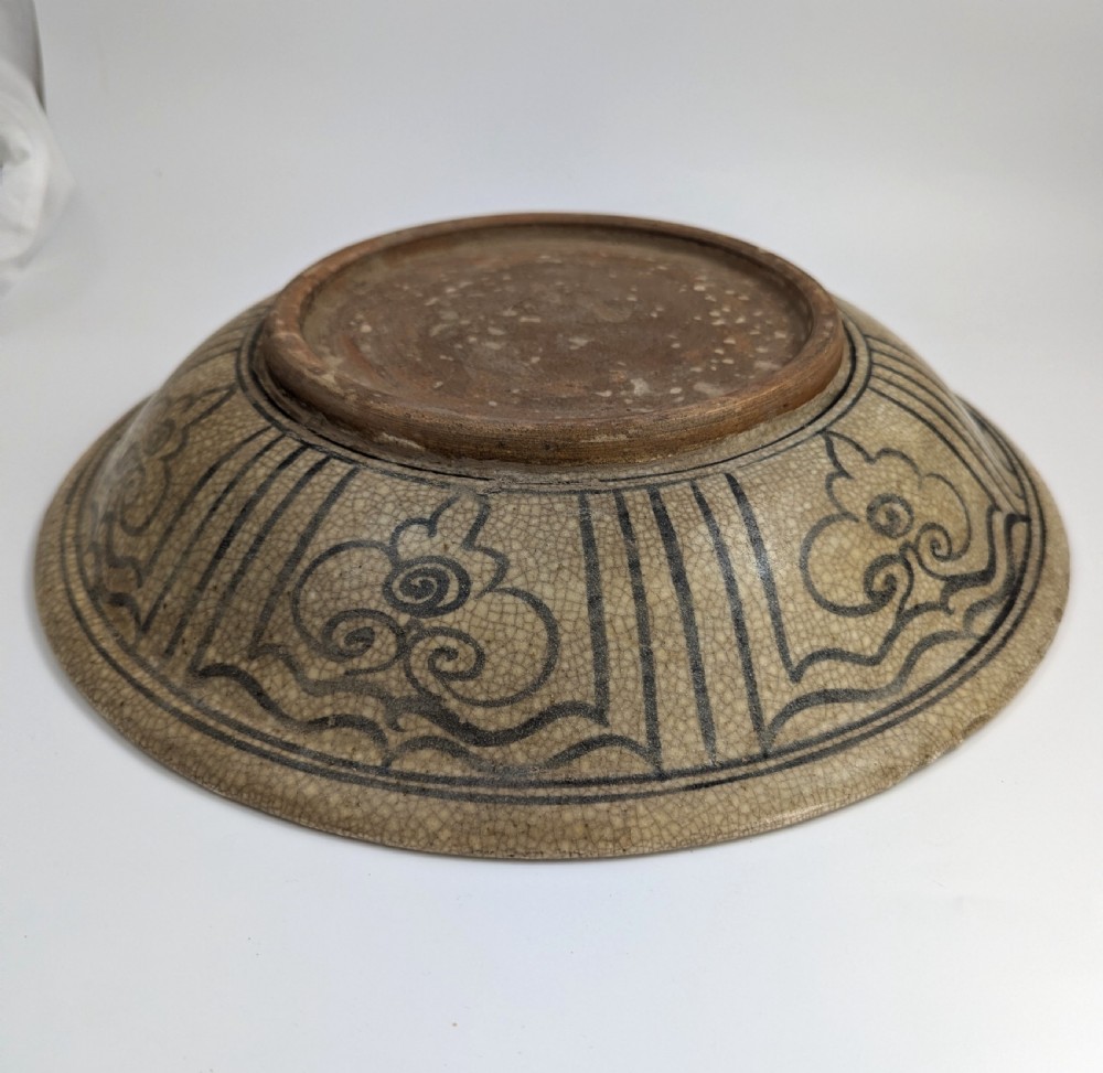 A circular antique ceramic dish featuring a central underglaze grey fish design on a crazed cream ground. View VIII
