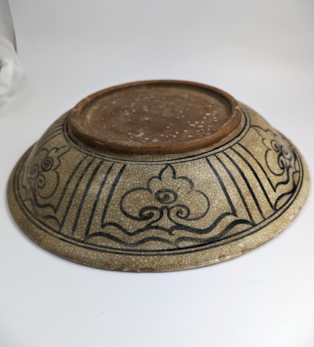 A circular antique ceramic dish featuring a central underglaze grey fish design on a crazed cream ground. View IX