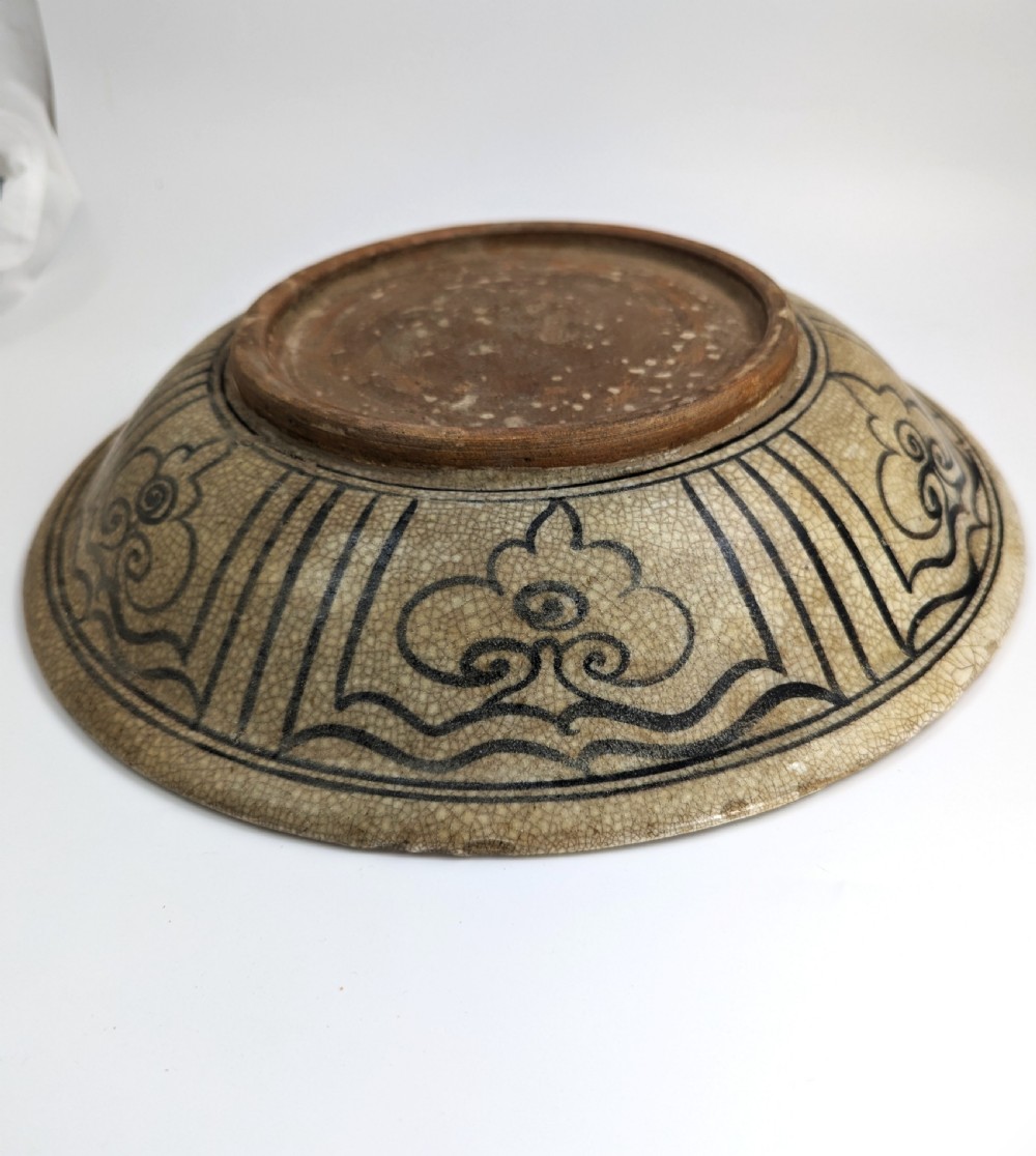 A circular antique ceramic dish featuring a central underglaze grey fish design on a crazed cream ground. View X