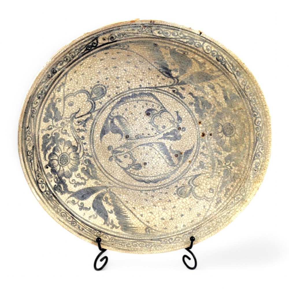 A circular antique ceramic dish featuring a central underglaze grey fish design on a crazed cream ground.