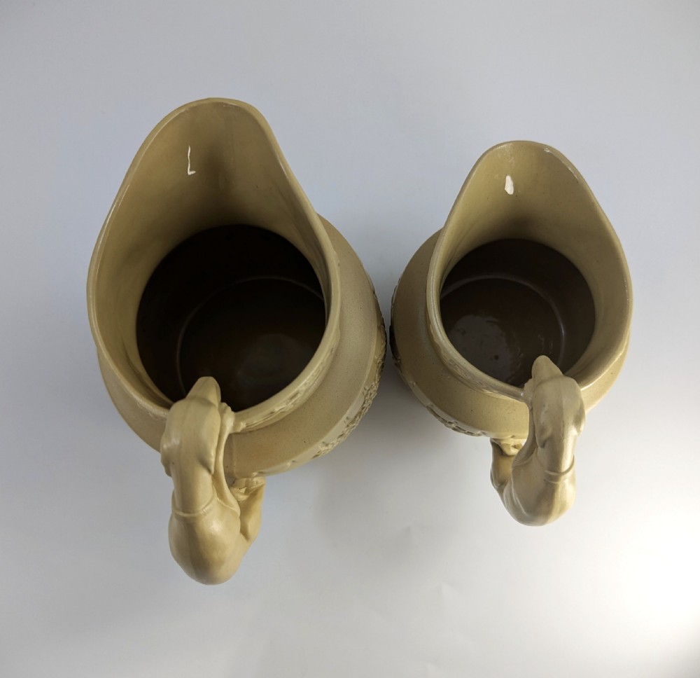 A graduated set of three buff yellow Regency ceramic pitchers featuring relief-moulded stag hunting scenes and sculpted hound handles. View VII