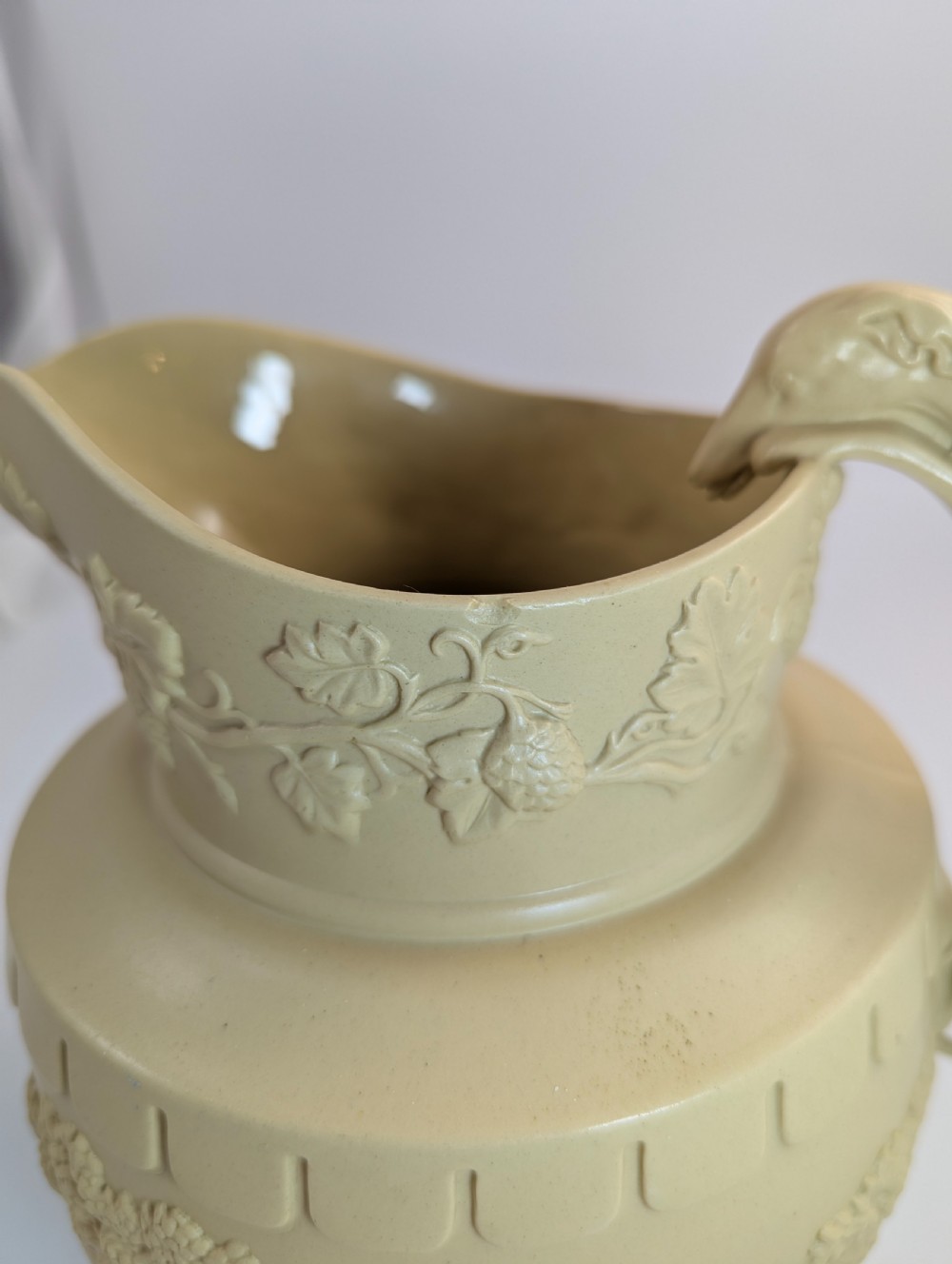 A graduated set of three buff yellow Regency ceramic pitchers featuring relief-moulded stag hunting scenes and sculpted hound handles. View X