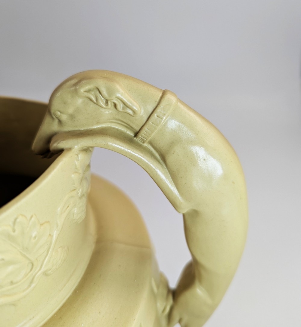 A graduated set of three buff yellow Regency ceramic pitchers featuring relief-moulded stag hunting scenes and sculpted hound handles. View XI