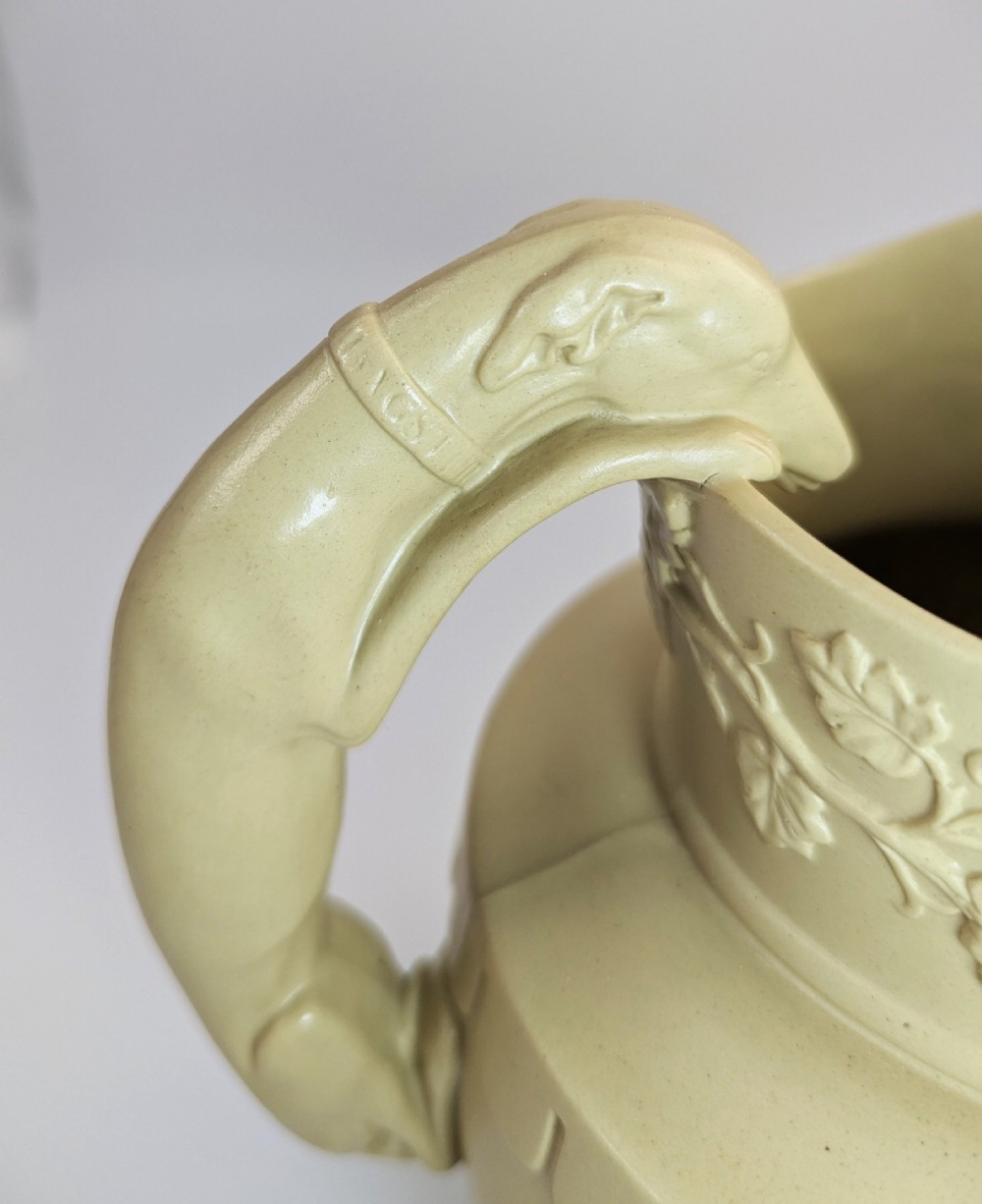 A graduated set of three buff yellow Regency ceramic pitchers featuring relief-moulded stag hunting scenes and sculpted hound handles. View XII