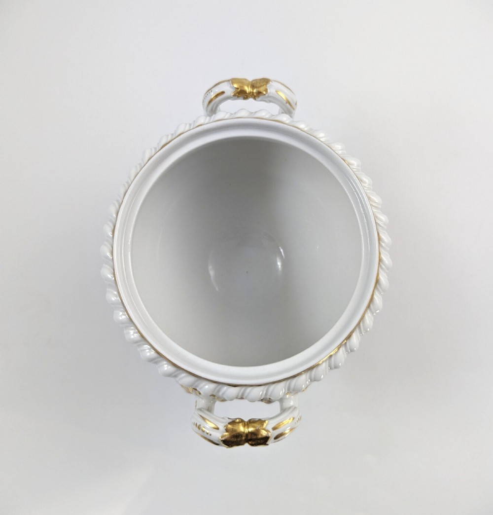 A white Regency porcelain sauce tureen decorated with orange and blue floral Imari motifs, featuring twin gilded handles, a square pedestal base, and a domed lid with a gilded finial. View VI