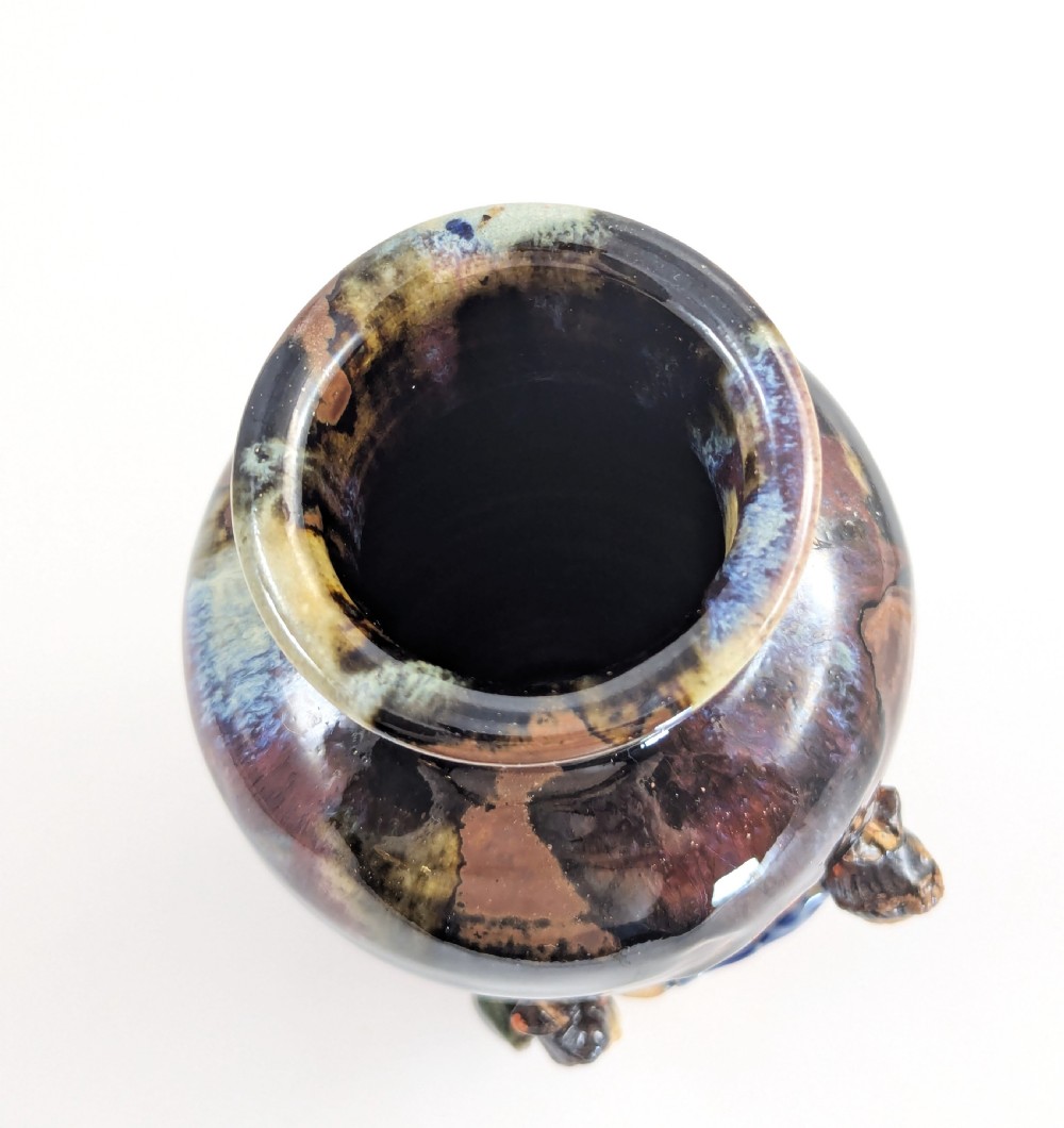 A Japanese Sumida Gawa pottery vase featuring an oxblood flambe glazed neck and applied relief figures on a ribbed terracotta body. View VII