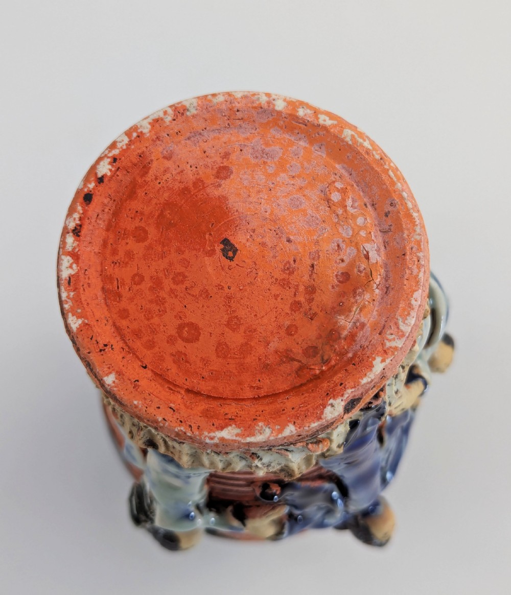 A Japanese Sumida Gawa pottery vase featuring an oxblood flambe glazed neck and applied relief figures on a ribbed terracotta body. View VIII