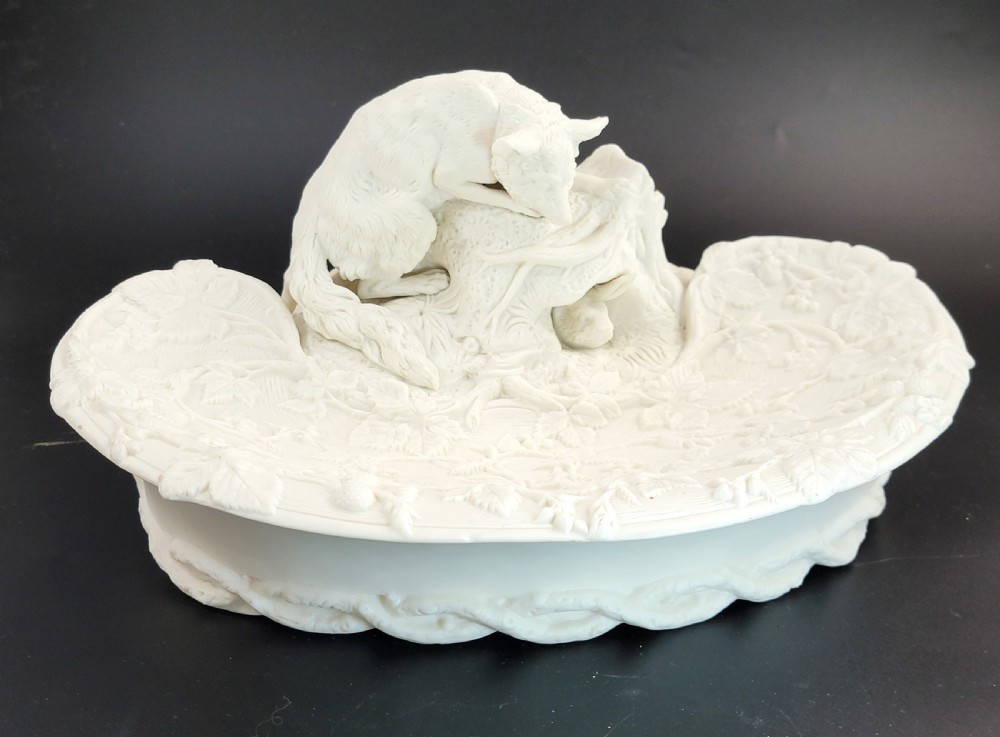 An off-white Parian porcelain centrepiece dish featuring a sculpted fox perched on a central stump above a rabbit in a hollow base surrounded by leaves.