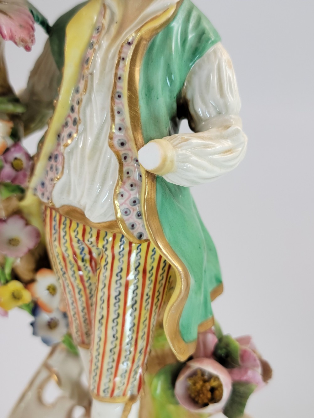 A pair of 18th-century Georgian Derby soft-paste porcelain figural candlesticks depicting a male and female figure in period dress beside candle sconces adorned with colourful flowers and gilt Rococo scrollwork. View VIII